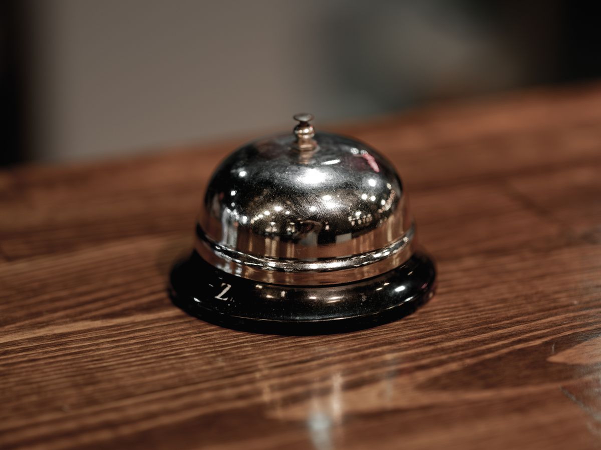 Eine Empfangsglocke auf einem Holztresen an einer Hotelrezeption